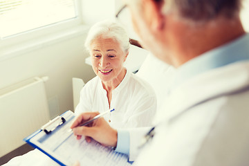 Image showing senior woman and doctor with clipboard at hospital