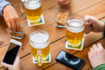 Image showing close up of hands with smartphones and beer at bar