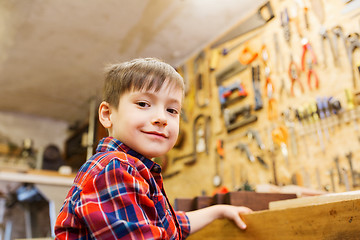 Image showing happy little boy with wood plank at workshop