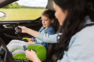 Image showing happy woman fastening child with seat belt in car