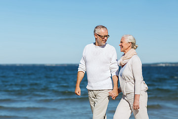 Image showing happy senior couple holding hands on summer beach