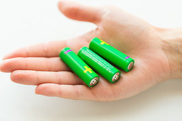 Image showing close up of hand holding green alkaline batteries