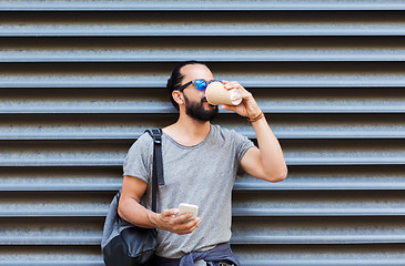 Image showing man with smartphone drinking coffee on city street