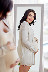 Image showing happy pregnant woman looking to mirror at home