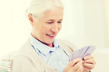 Image showing happy senior woman playing cards at home