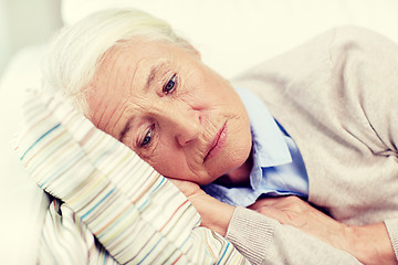 Image showing sad senior woman lying on pillow at home