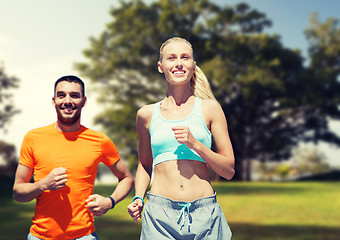 Image showing smiling couple running over summer park background