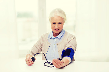 Image showing old woman with tonometer checking blood pressure