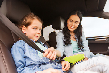 Image showing happy woman fastening child with seat belt in car