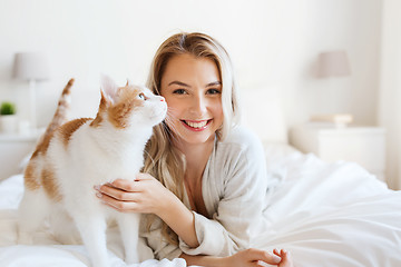 Image showing happy young woman with cat in bed at home