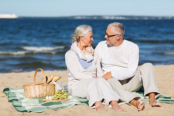 Image showing happy senior couple having picnic on summer beach