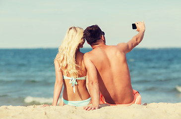 Image showing happy couple in swimwear sitting on summer beach