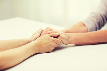 Image showing close up of senior and young woman holding hands