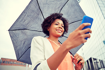 Image showing businesswoman with umbrella texting on smartphone