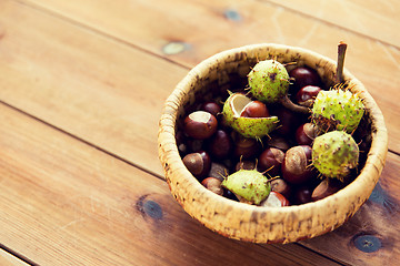 Image showing close up of chestnuts in basket on wooden table