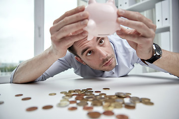 Image showing businessman with piggy bank and coins at office