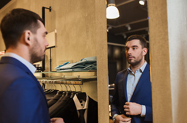 Image showing man trying jacket on at mirror in clothing store