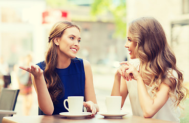 Image showing young women drinking coffee and talking at cafe