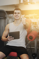 Image showing smiling young man with tablet pc computer in gym