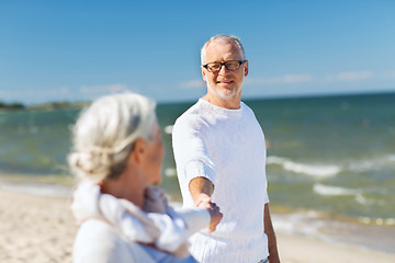 Image showing happy senior couple holding hands on summer beach