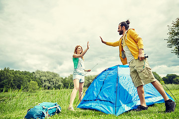 Image showing happy couple setting up tent outdoors