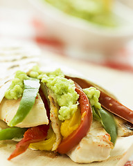 Image showing delicious wrap tortilla with spicy chicken vegetables guacamole