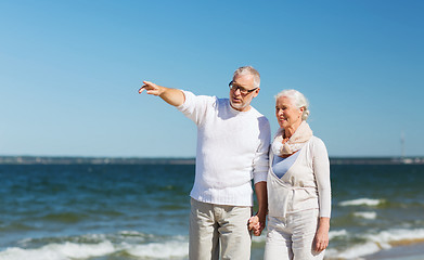 Image showing happy senior couple walking on summer beach