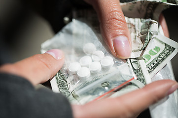 Image showing close up of addict hands with drugs and money