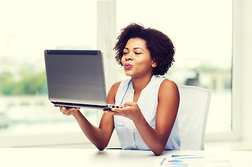 Image showing african woman sending kiss to laptop computer