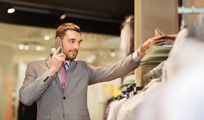 Image showing happy man calling on smartphone at clothing store