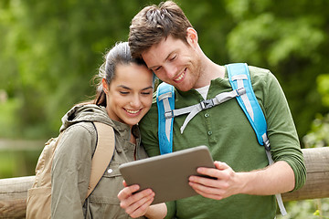 Image showing happy couple with backpacks and tablet pc outdoors