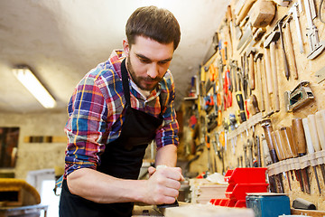 Image showing carpenter working with plane and wood at workshop