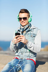 Image showing happy young man in headphones with smartphone