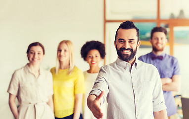 Image showing happy man making handshake over office team