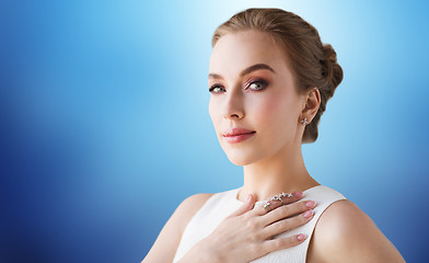 Image showing smiling woman in white dress with diamond jewelry