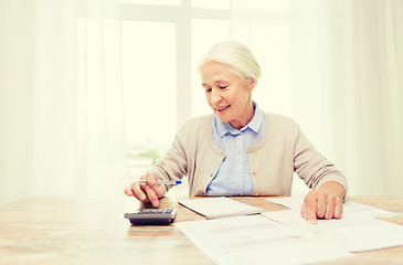 Image showing senior woman with papers and calculator at home