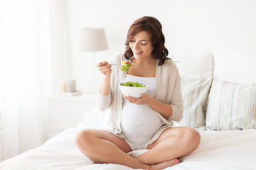 Image showing happy pregnant woman eating salad at home