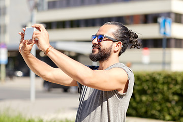 Image showing man taking video or selfie by smartphone in city