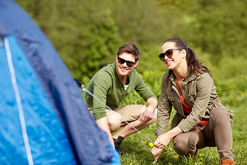 Image showing happy couple setting up tent outdoors