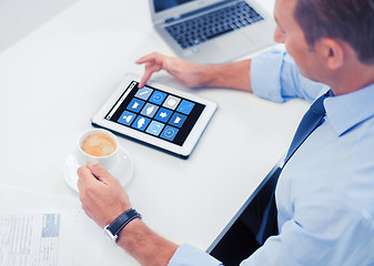 Image showing businessman with app icons on tablet pc and coffee