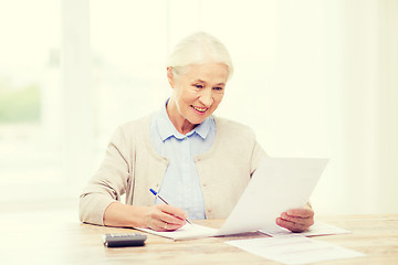 Image showing senior woman with papers and calculator at home