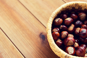 Image showing close up of chestnuts in basket on wooden table