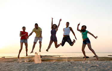 Image showing smiling friends dancing and jumping on beach