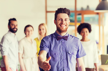 Image showing happy man making handshake over office team