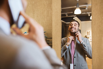 Image showing man calling on smartphone at clothing store mirror