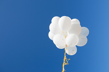 Image showing close up of white helium balloons in blue sky