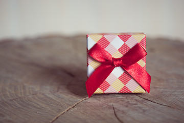 Image showing Gift box with red bow on wood background