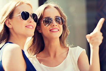 Image showing happy women in sunglasses pointing finger outdoors