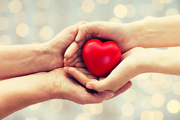 Image showing senior and young woman hands holding red heart