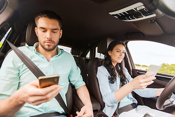 Image showing man and woman with smartphones driving in car